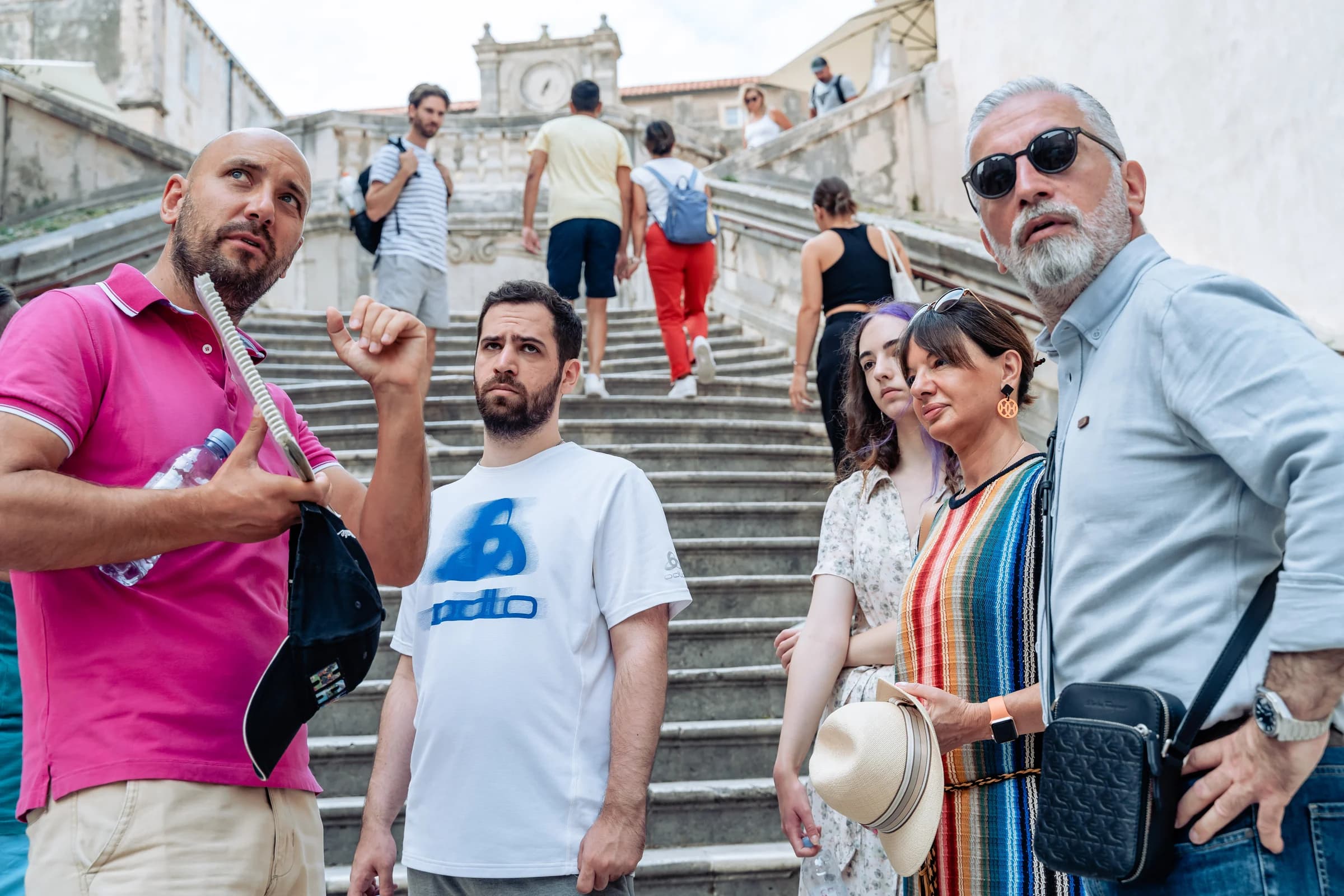 A guide speaking with visitors beside a broad stone staircase in Dubrovnik.