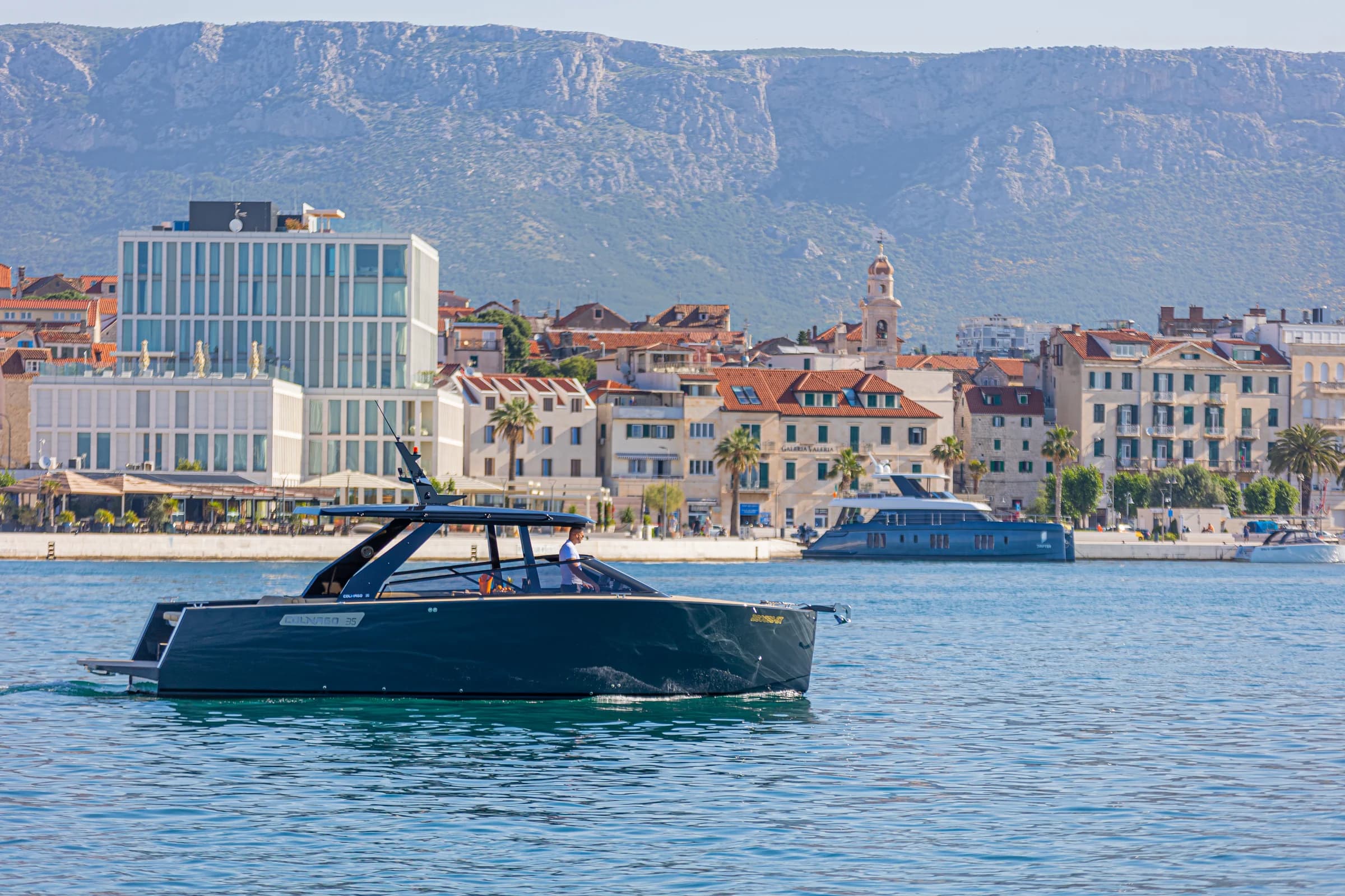 A boat in the water in front of the city waterfront.