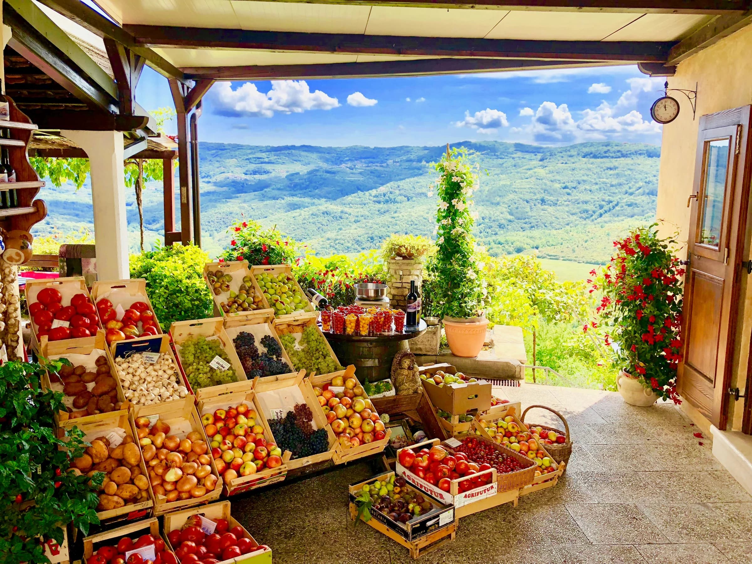 Local produce, jars and bottles displayed beneath a canopy with a view of the hills.