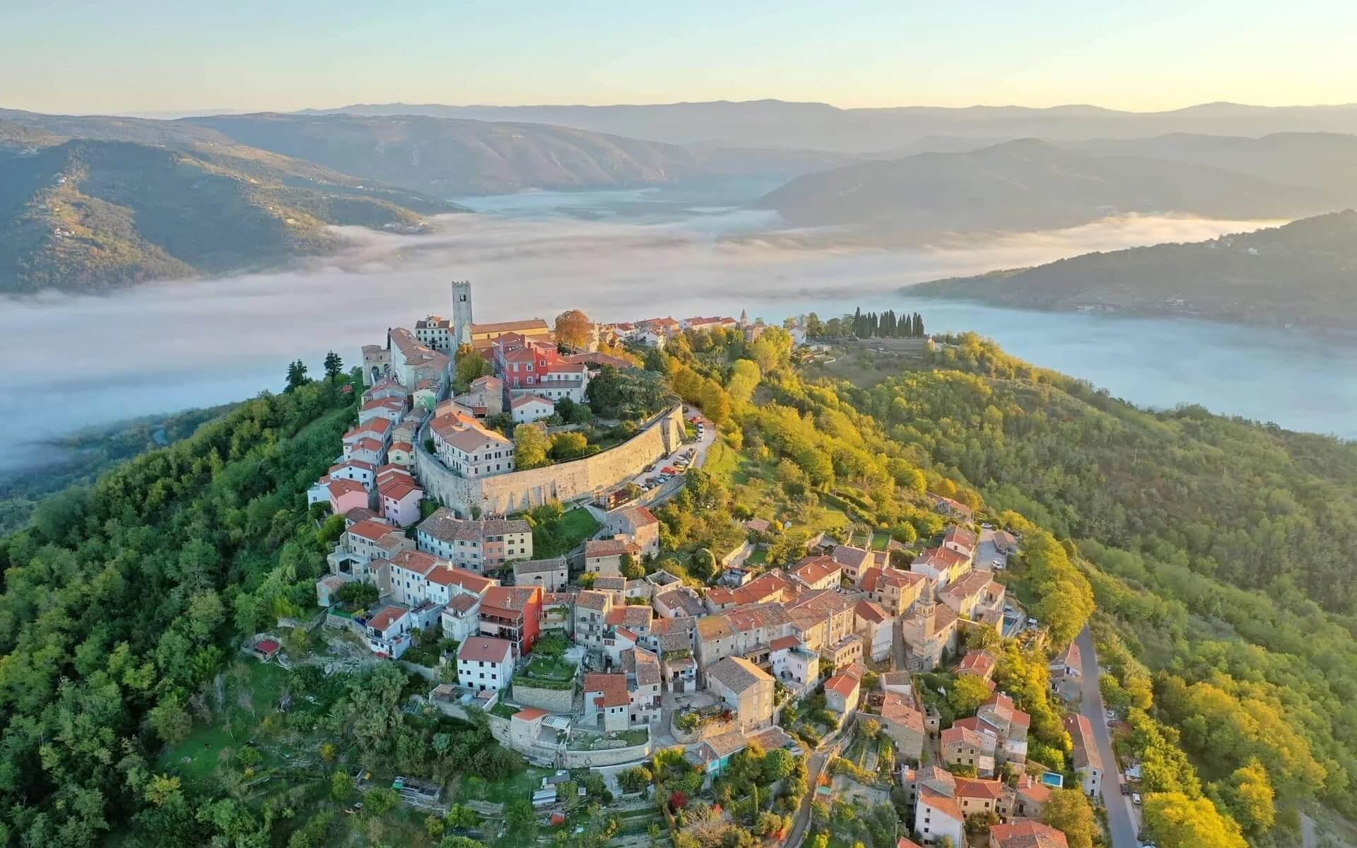 Motovun on a wooded hill above a misty valley.