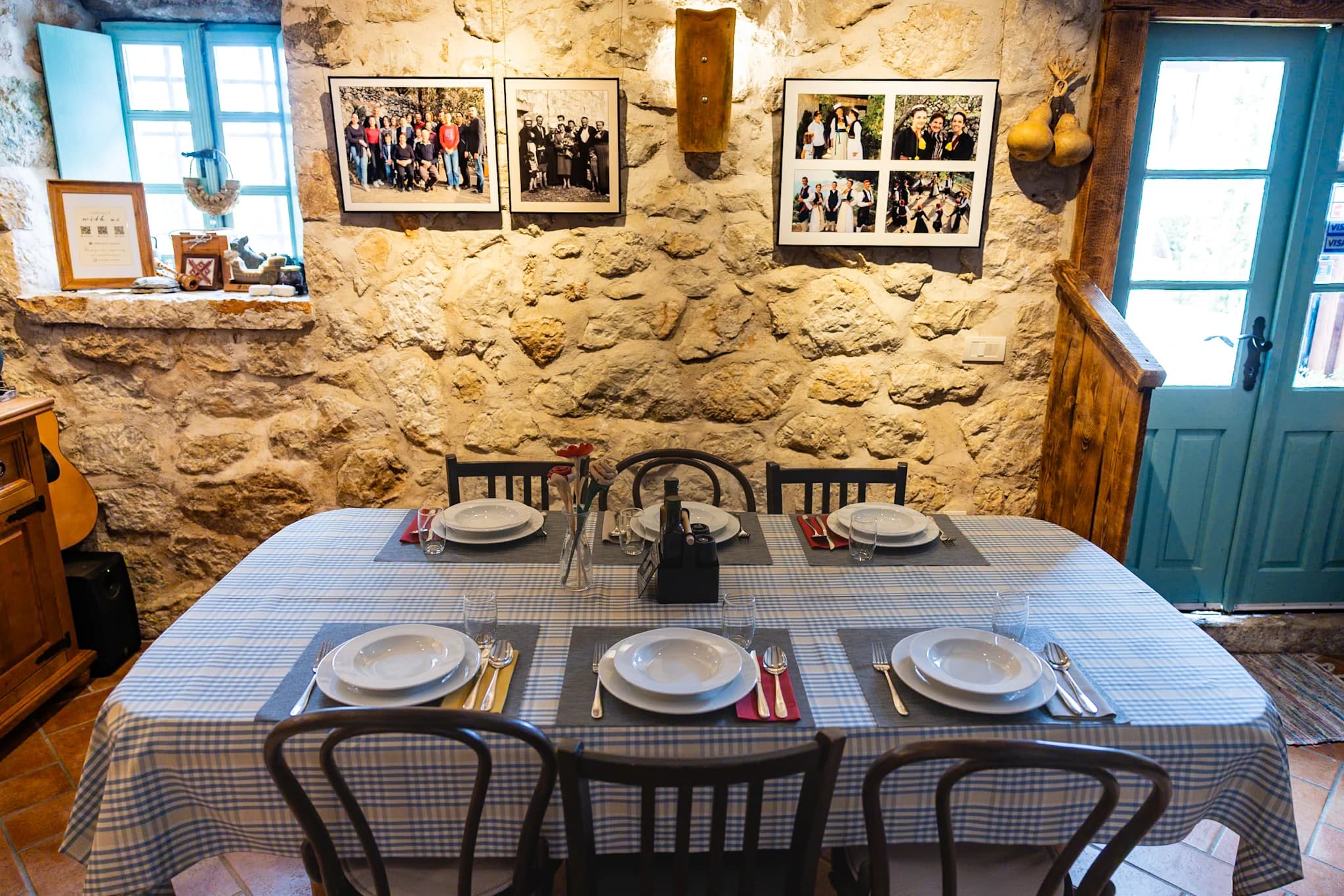 A table set with plates and glasses in a stone room decorated with family photographs.