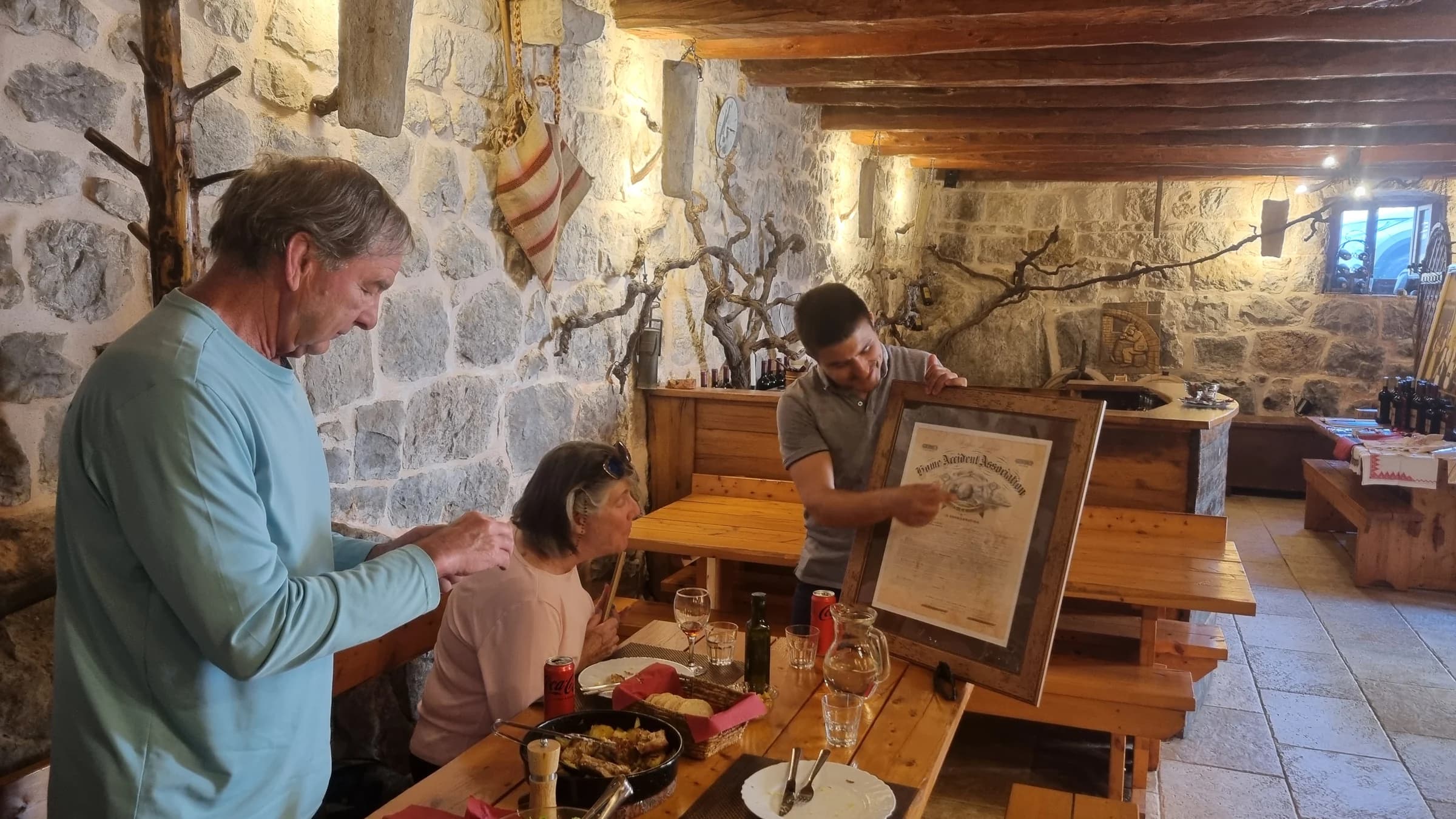 Guests gathered around food and glasses on a wooden table in a stone interior.