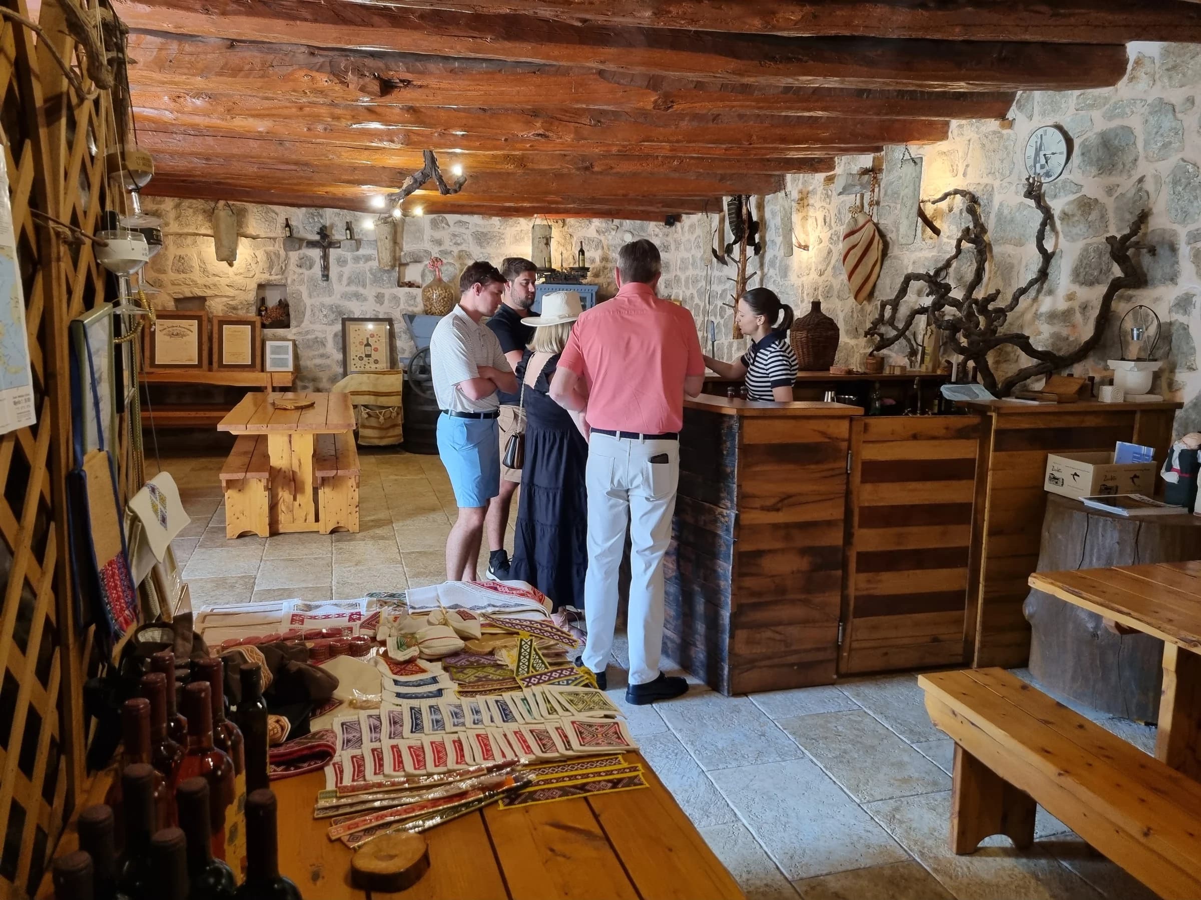 People gathered around a wooden counter inside a rustic stone cellar.