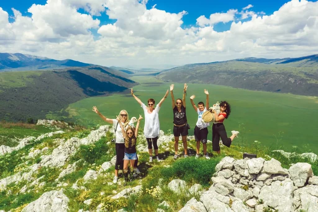 Visitors posing among limestone rocks above a broad green valley.