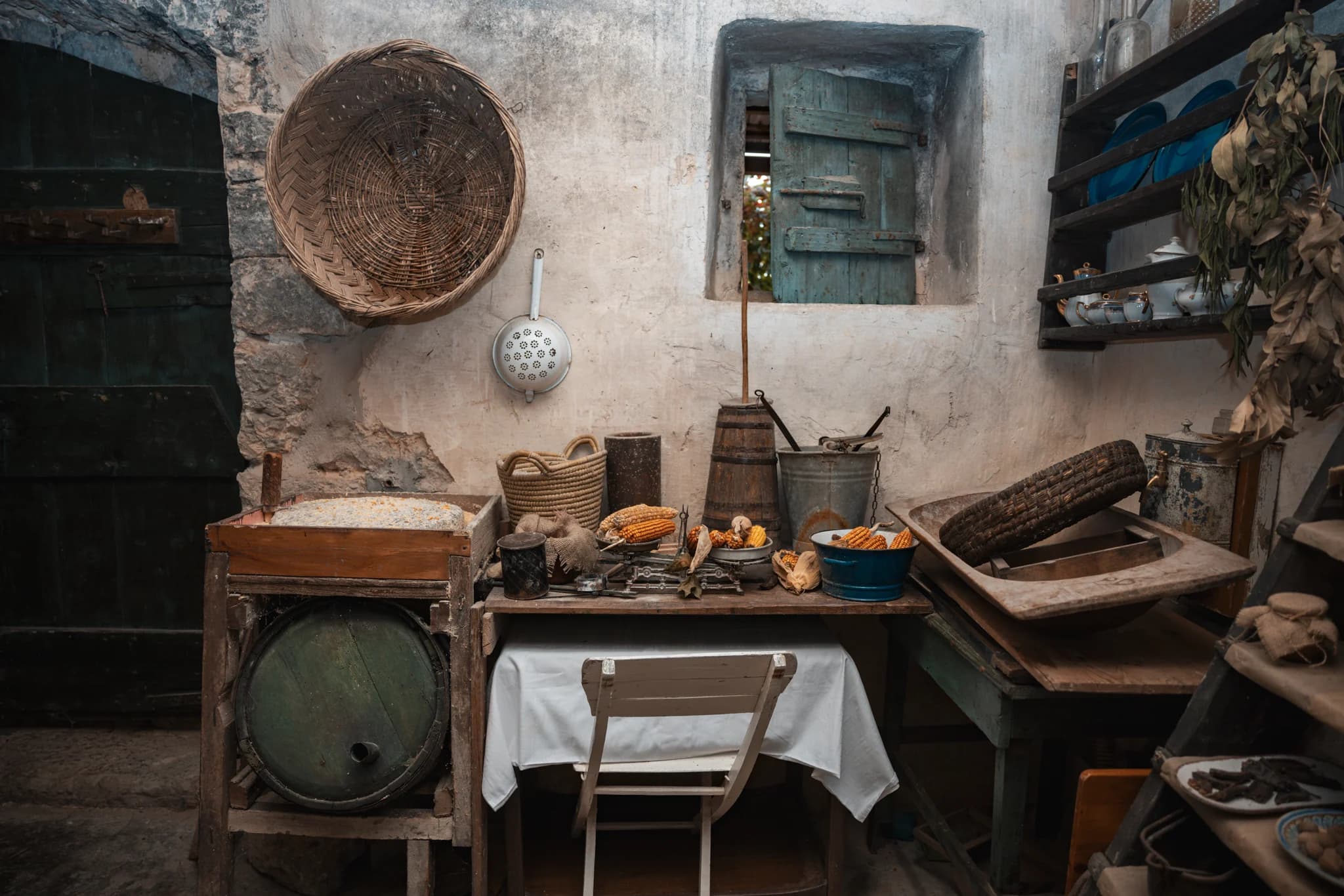 An old stone-walled kitchen with wooden work surfaces, utensils and a small laid table.