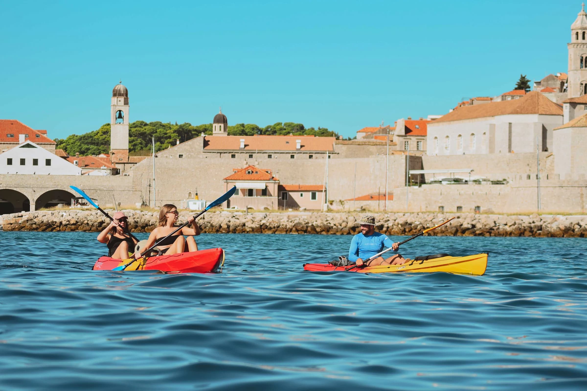 Kayakers paddling beside Dubrovnik's stone city walls.