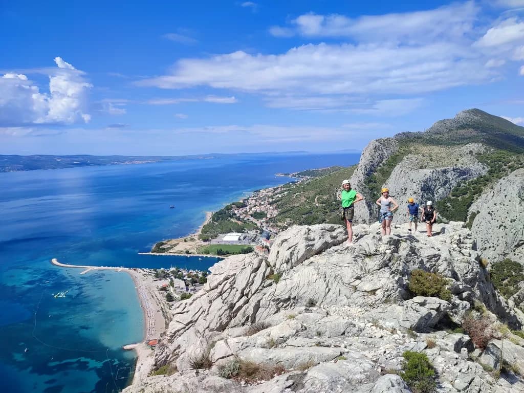 Walkers on a rocky ridge overlooking the beach, town and Adriatic.