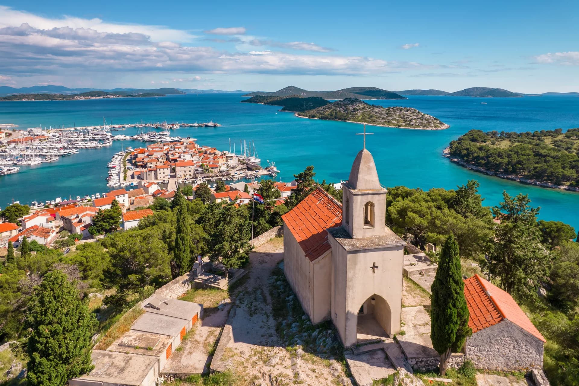 A coastal town and its harbour look out toward a chain of islands.