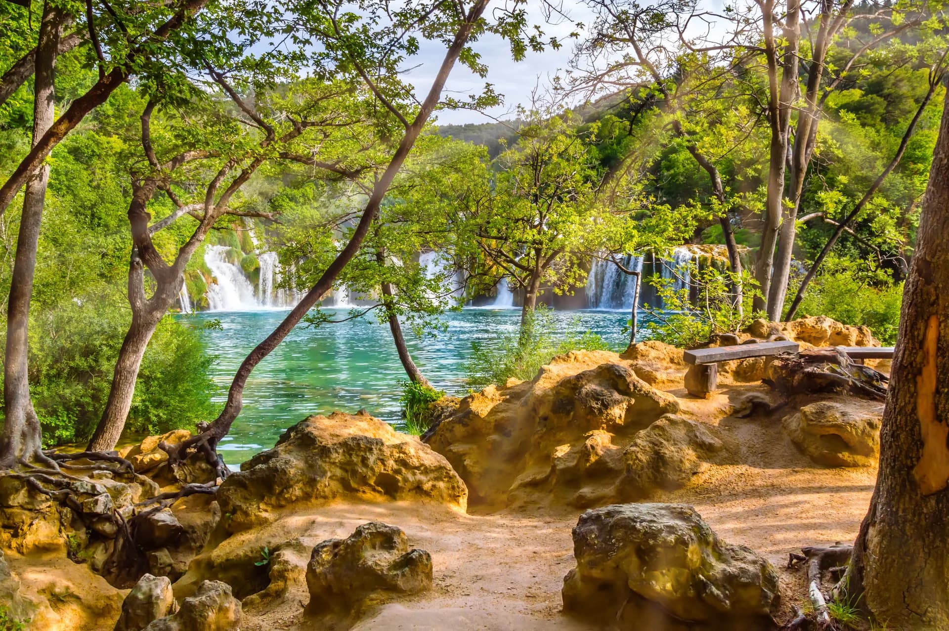 Waterfalls and turquoise pools framed by shaded woodland.