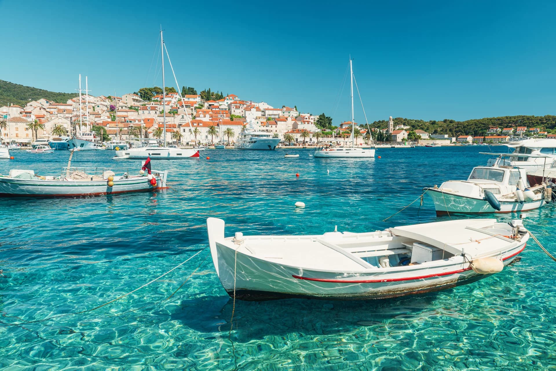 Wooden boats moored in clear harbour water.