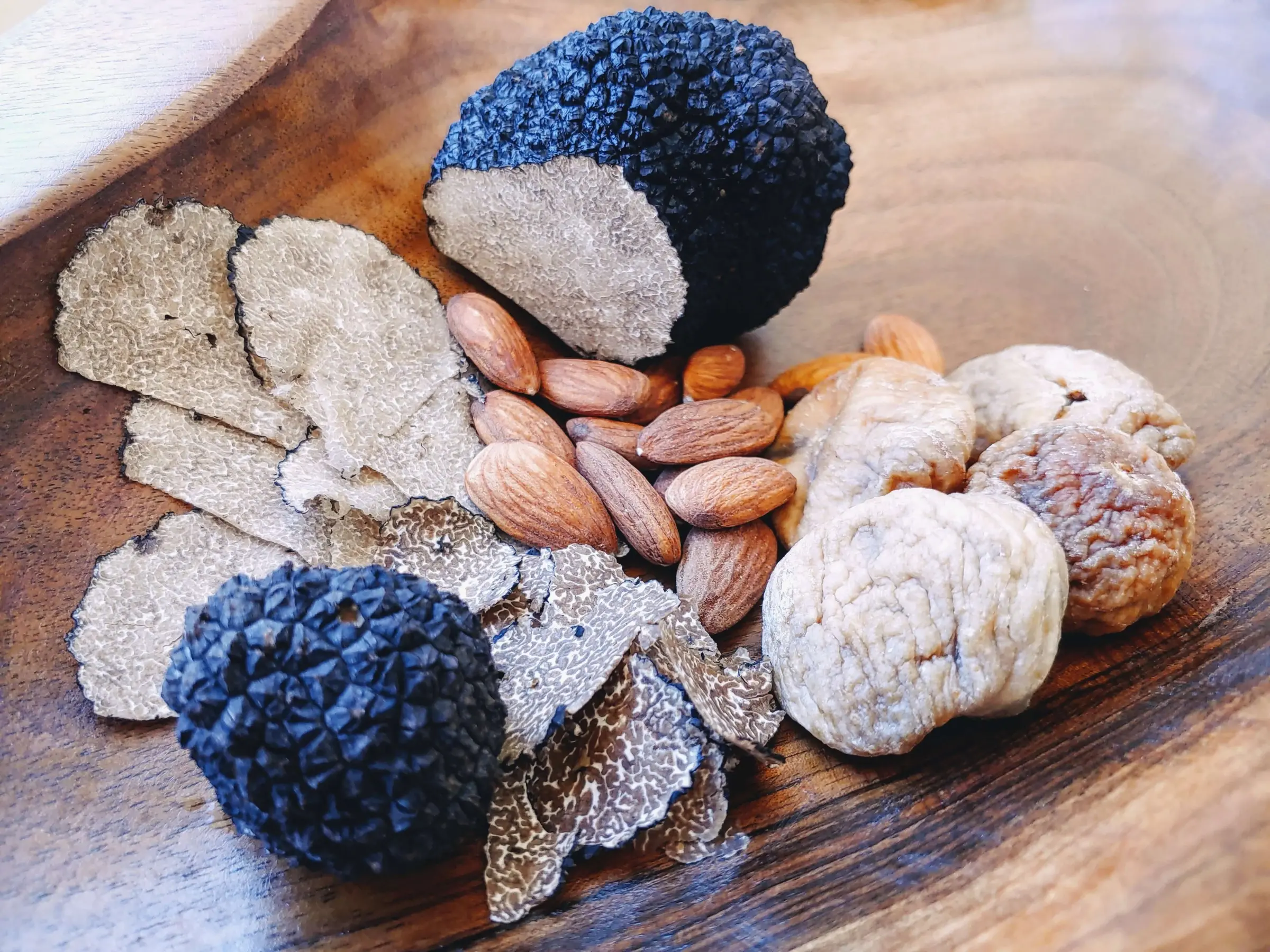 Whole and sliced truffles on a wooden board.